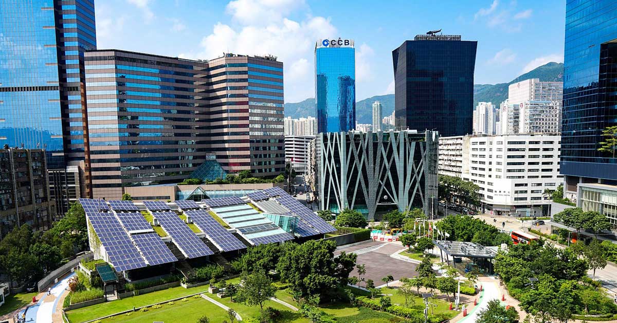A vibrant city skyline with numerous solar panels on buildings set against a lush green lawn, symbolizing the Energy Revolution. Photo: Jude Joshua from Pixabay